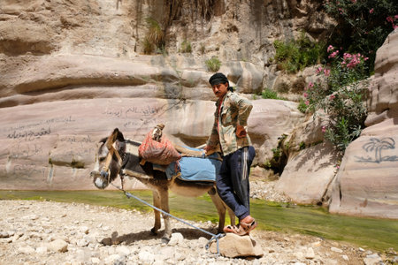 Dana Biosphere Reserve, Jordan - circa May 2022: Jordanian man is standing with donkey in Wadi Ghuweir Canyon. He is goat shepherd.のeditorial素材