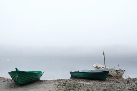 Wooden boats on shore of lake in calm misty day.の写真素材