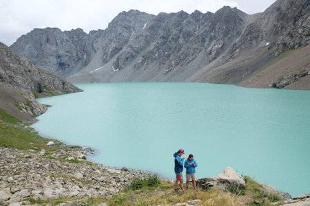 Tien Shan, Ala Kol Lake, Kyrgyzstan - circa August 2022: Silhouette of to woman by amazing lake Ala-KÃ¶l (Ala-kol, Ala-kul) in Tien Shan mountains, west of Kyrgyzstan, Asia. Caracolのeditorial素材