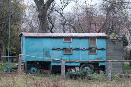 Old wooden barrack on wheels stands among trees.の写真素材