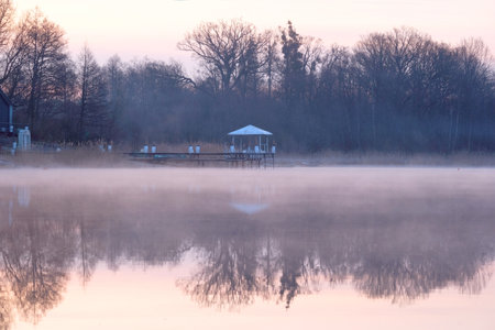 Beautiful scenery of wooden pier by misty lake in morning light. Otomin Lake, Kashubia, Polandの写真素材
