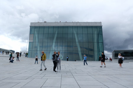 Norway, Oslo - July 25, 2023: National Oslo Opera House and people walking around it. Symbol of capital city in summer sunny and cloudy sceneryのeditorial素材