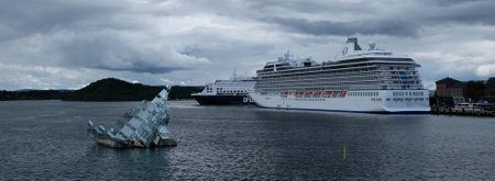 OSLO, NORWAY - JULY 25, 2023: Floating sculpture She Lies looking like iceberg and big cruise ship in background in the Oslo Fjord. Sunny and cloudy weather, dramatic cousds on skyのeditorial素材