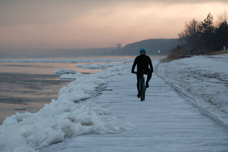 Silhouette of cyclist on wharf on frozen concrete wharf by estuary of Vistula river, Sobieszewska Island, Poland.の写真素材