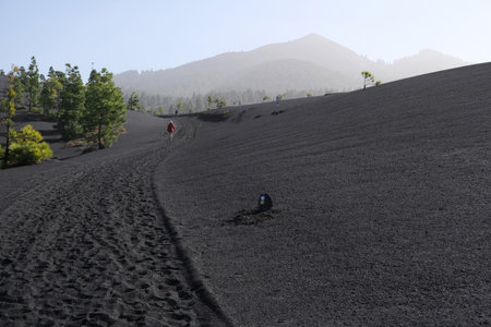 Amazing volcanic scenery around volcan Montana Quemada (Volcan Tacande) and silhouettes of hiking tourist on trail from El Paso to De Pilar on La Palma, Canary Islands, Spainの写真素材