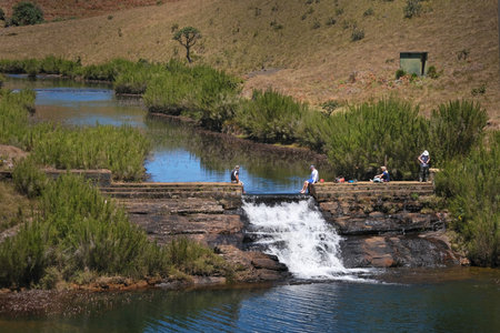 Beautiful scenery of Chimney Pool, Horton Plains National Park, Sri Lanka. Silhouettes of resting tourists by cascade.の写真素材
