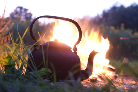 An old metal kettle stands by campfireの写真素材