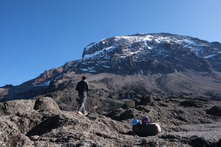 Silhouette of standing man and Kilimanjaro peak in background, on trail from Barranco Hut to Barafu Camp, during trekking to Kilimanjaro Peak, Machame Route. Tanzaniaの写真素材
