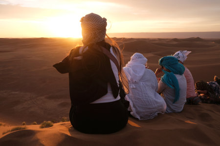 Girls sitting on dune during sunset over desert. Sahara, Moroccoの写真素材