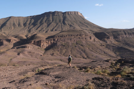 Amazing mountain landscapes of Jebel Saghro with volcanic rocks eroded by wind and time and little silhouette of single man. Atlas, Anti Atlas, Moroccoの写真素材