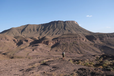 Amazing mountain landscapes of Jebel Saghro with volcanic rocks eroded by wind and time and little silhouette of single man. Atlas, Anti Atlas, Moroccoの写真素材