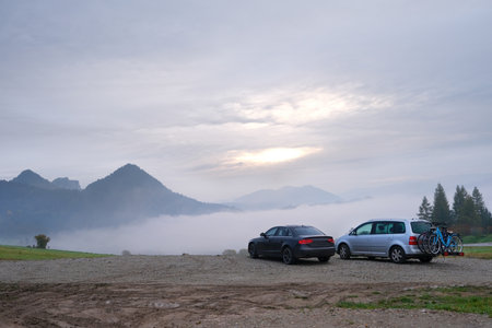 Two cars are standing on mountain viewpoint in misty scenery in Pieniny Mountains, Polandの写真素材