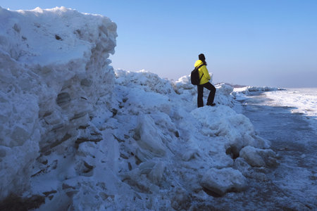 Ice toros (mountains of piled-up ice) on the beach in Mikoszewo, Baltic Sea, Pomerania, Poland. This is a very interesting and rare phenomenon. Silhouette of woman standing on ice.の写真素材