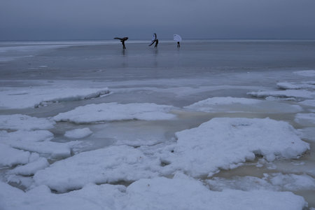 Frozen Bay of Puck (Baltic Sea) and little silhouettes of people with wings on ice, Pomerania,...