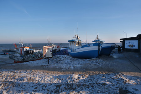 Fishing harbor with fishing boats moored on the shore in winter conditions in Mielno (UnieÅ›cie),...