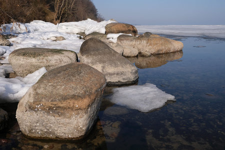 Early spring in Puck Bay by Baltic Sea with big stones in water and ice on surface of sea. Oslonino, Pomerania, Polandの写真素材