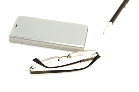 Smartphone, glasses and pen on a white backgroundの写真素材