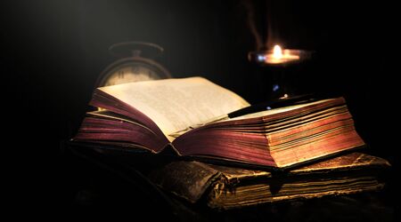 Holy Bible open and candlelight in a darkの写真素材