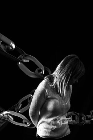 Woman trapped in chains. Photography symbolizing captivity or violence against woman.の写真素材