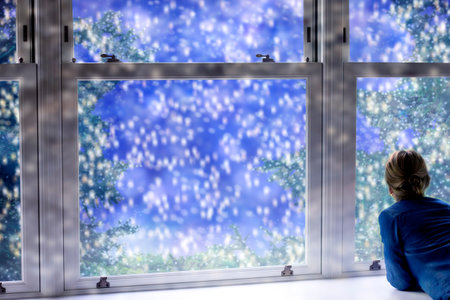 Christmas background with a woman looking at falling snow outside the window. Winter background.の写真素材
