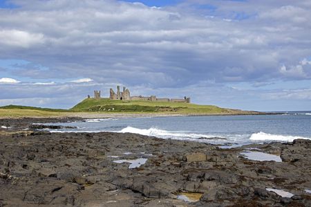 Dunstanburgh Castle from the coastal path to Craster with shoreline in the foregroundの写真素材
