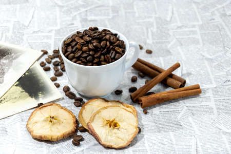 Afternoon black coffee in a white cup. Sweet dessert. Dried apples and cinnamon.の写真素材