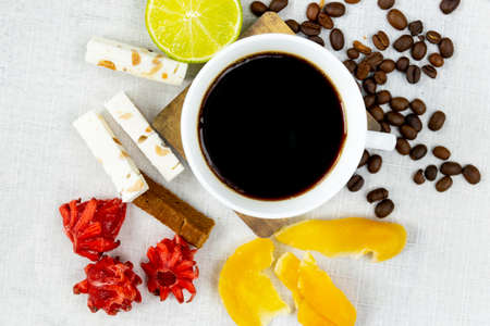 Afternoon black coffee in a white cup. Sweet dessert. Mango fruit and hibiscus flowers.の写真素材