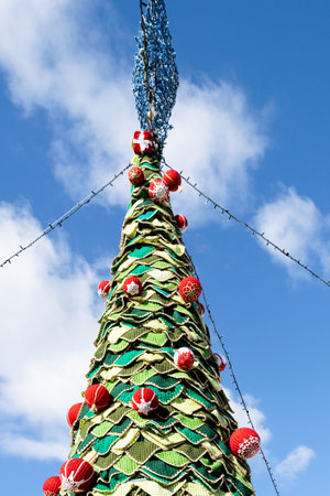 Christmas tree decorated with red and green balls on blue sky background.の写真素材