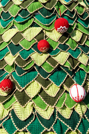 Christmas tree decorated with red and green balls against the blue sky. Handmade crochet Christmas tree.の写真素材