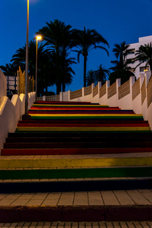 Colorful stairs illuminated in a park at night in Nerja, Spain. Palm trees above the stairs.の写真素材