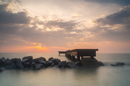Beautiful sunset view over calm water of an abandoned jetty in Bagan Sungai Burong, Malaysia because of erosionの写真素材