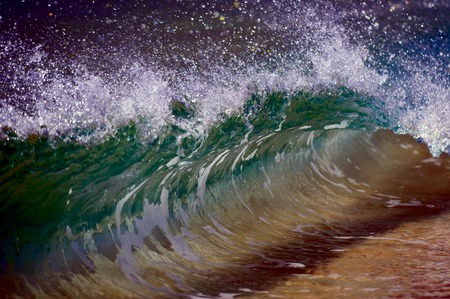A wave smashing on the sand shore