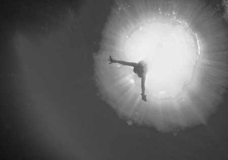 backlight diver underwater coming to the deep oceanの写真素材