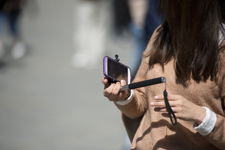 Hand making a selfie using remote control and extension tripodの写真素材