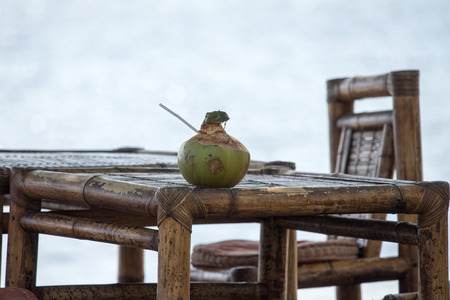 fresh coconut on bamboo table on the beach in tropical island paradise resort