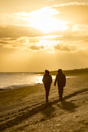 silhouette of man and woman at red sunrise background in patagonia beach in Argentinaの写真素材