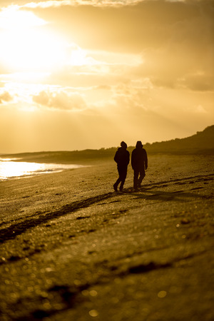 silhouette of man and woman at red sunrise background in patagonia beach in Argentinaの写真素材