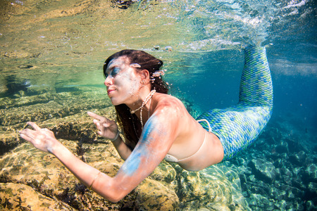 black hair Mermaid swimming underwater in the deep blue sea and looking at youの写真素材