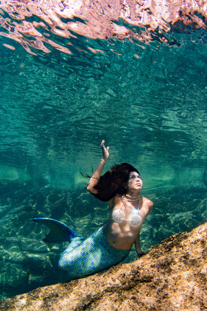 black hair Mermaid swimming underwater in the deep blue sea and coral reefの写真素材