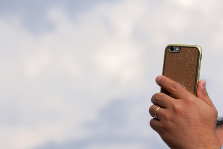hand taking picture with smartphone on soft sky color background