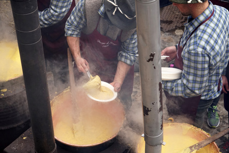 RANGO, ITALY - DECEMBER 1, 2017 - People cooking polenta traditional corn wheat meal at christmas market in the beautiful medieval villageのeditorial素材