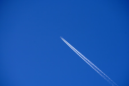 Jet Airplane trails tracks chemtrails in the deep blue sky background
