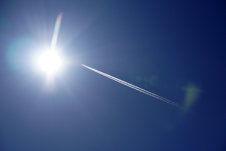 Jet Airplane trails tracks chemtrails in the deep blue sky backgroundの写真素材