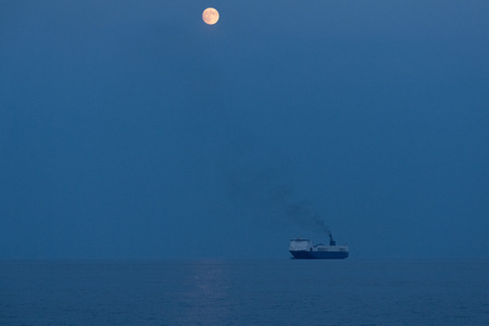 full moon ship at sunset harbor operationの写真素材