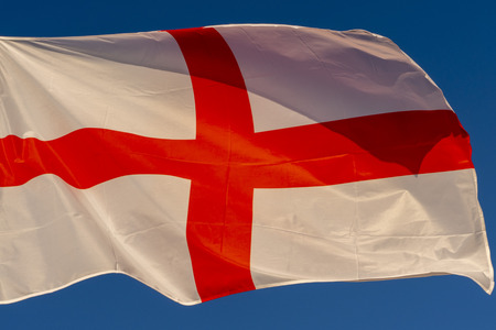 isolated waving english flag red cross on white on blue sky background