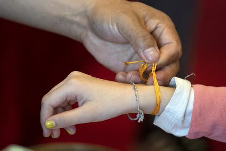 Tibetan monk while putting bracelet on buddihst hand detail