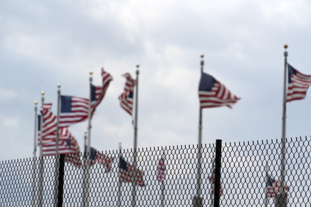 Waving usa flags behind metallic fence gridのeditorial素材