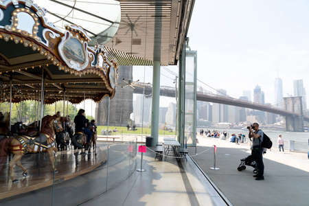 NEW YORK, USA, MAY 2 2019 - Brooklyn carousel on dumbo bridge full of tourists walking on sunny day