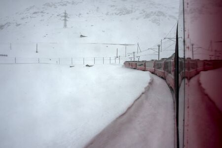 Red train running in the snow in swiss alps in winter