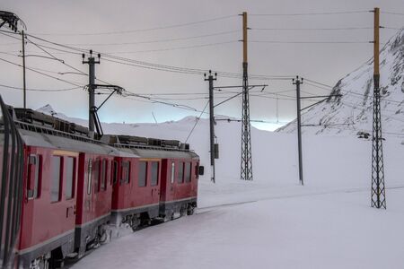 Red train running in the snow in swiss alps in winter